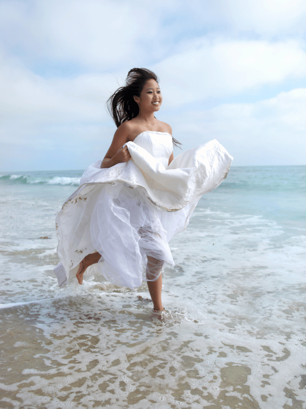 A bride runs through the shallow ocean