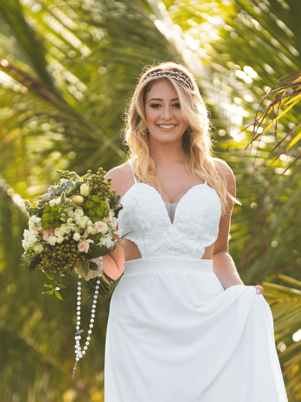 Portrait of boho bride with a bouquet and tropical foliage in the background