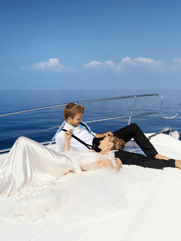 A bride and a groom lie down on the deck of a yacht