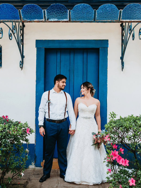 Bride and groom stand in front of blue door in Mediterranean-style building