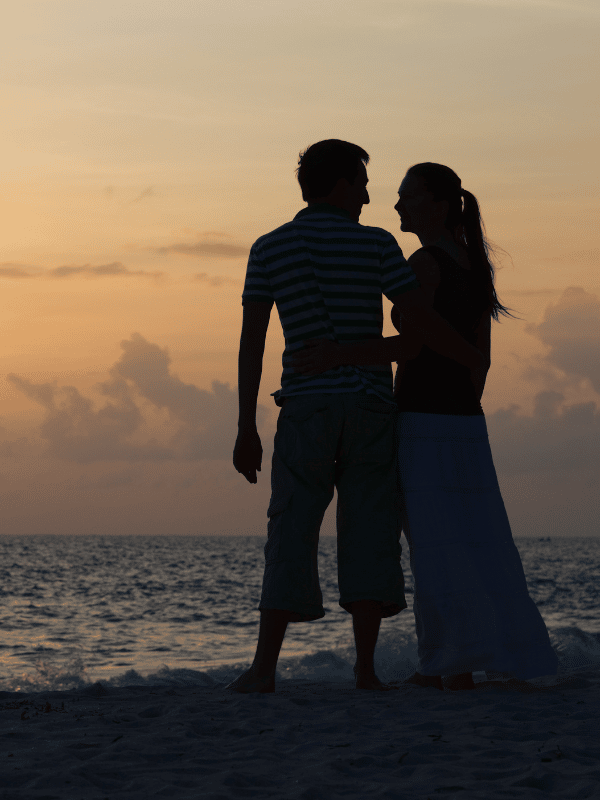 Silhouettes of a man and a woman on the beach at sunset
