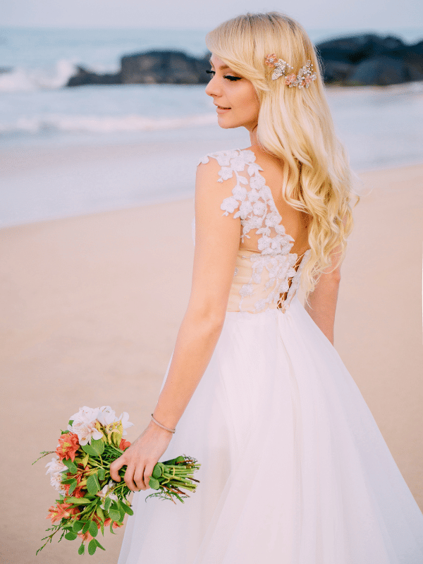 Portrait of a bride looking over her shoulder with a bouquet on the beach
