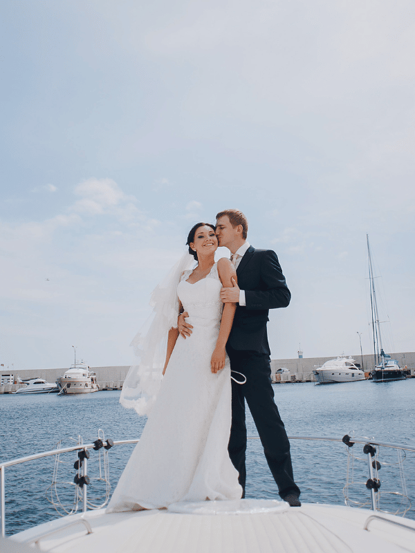 A bride and groom stand on the edge of a yacht
