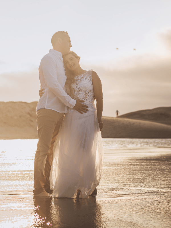Bride and groom on a misty golden beach at sunset