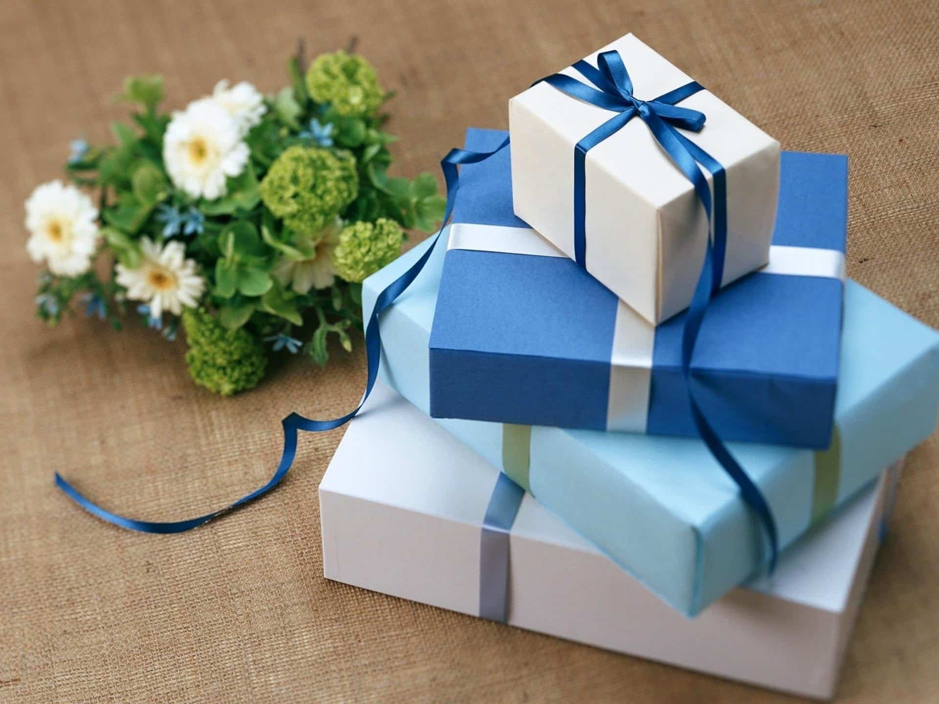 Three presents in a stack next to a bouquet.
