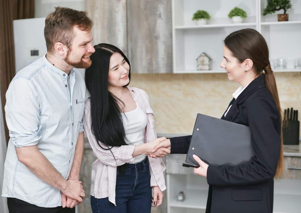 Man and woman shake hands with a business woman holding a planner