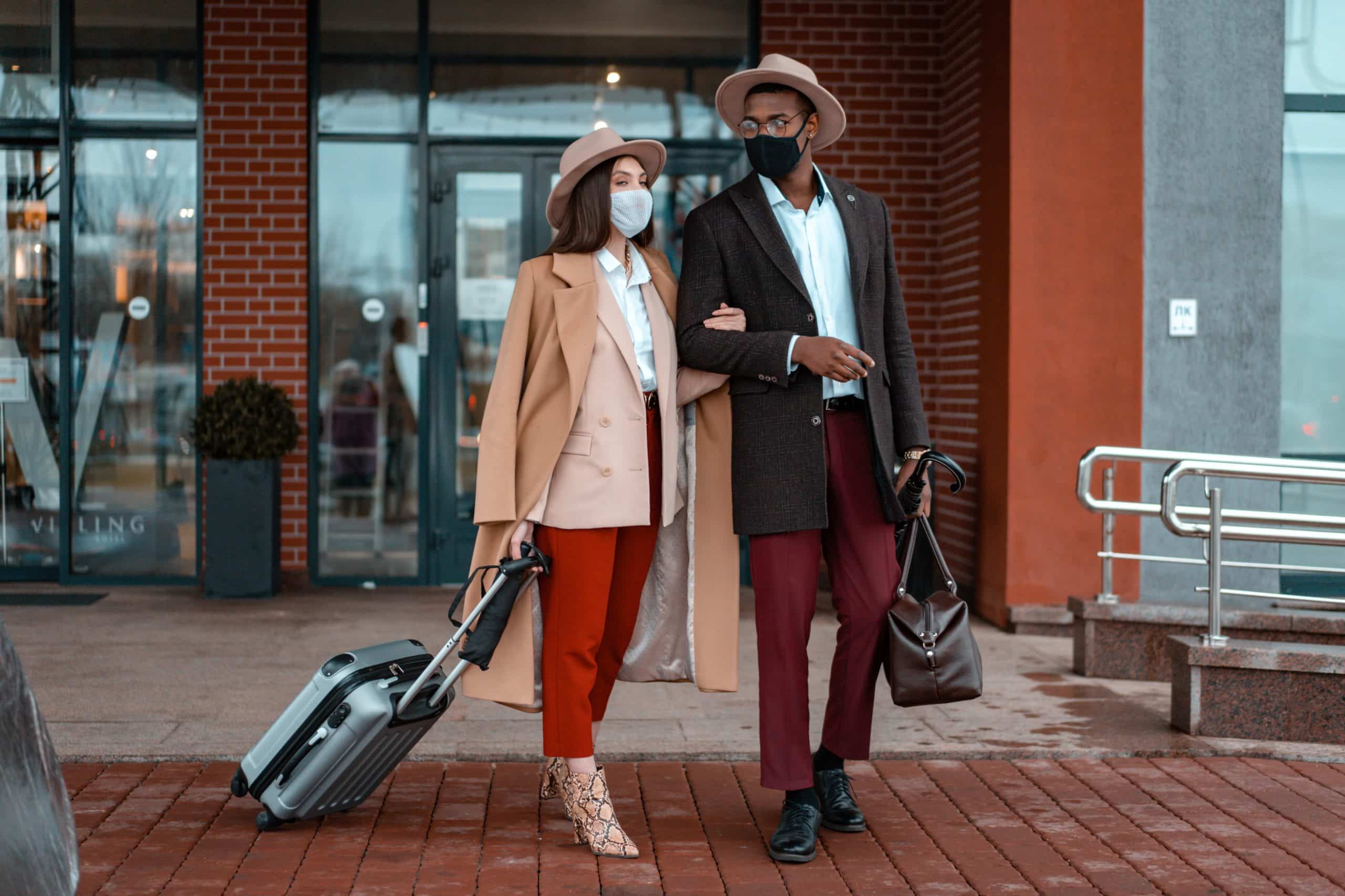Couple standing outside with suitcases