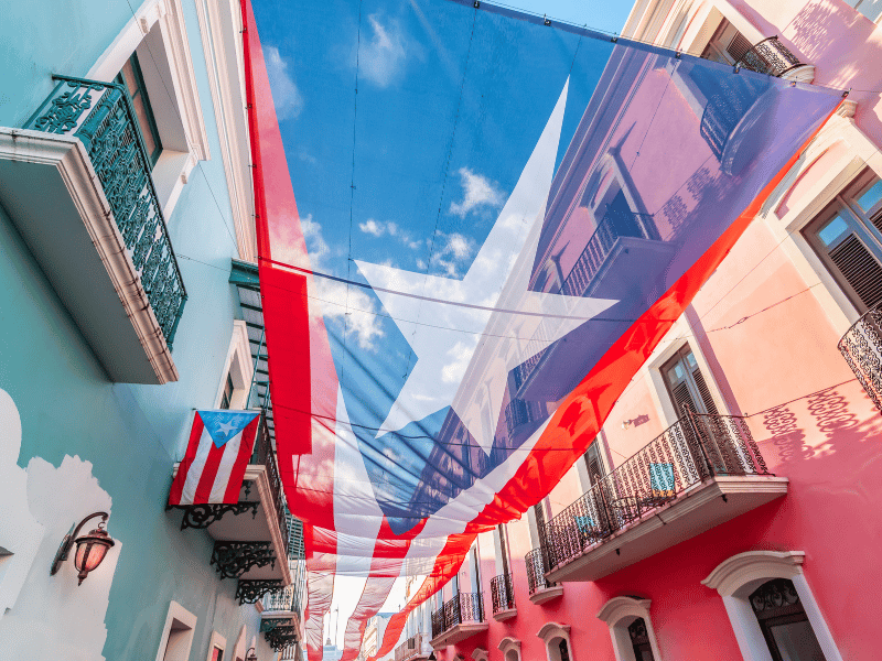 Blue and white buildings line the streets with a Puerto Rican flag hung between the two