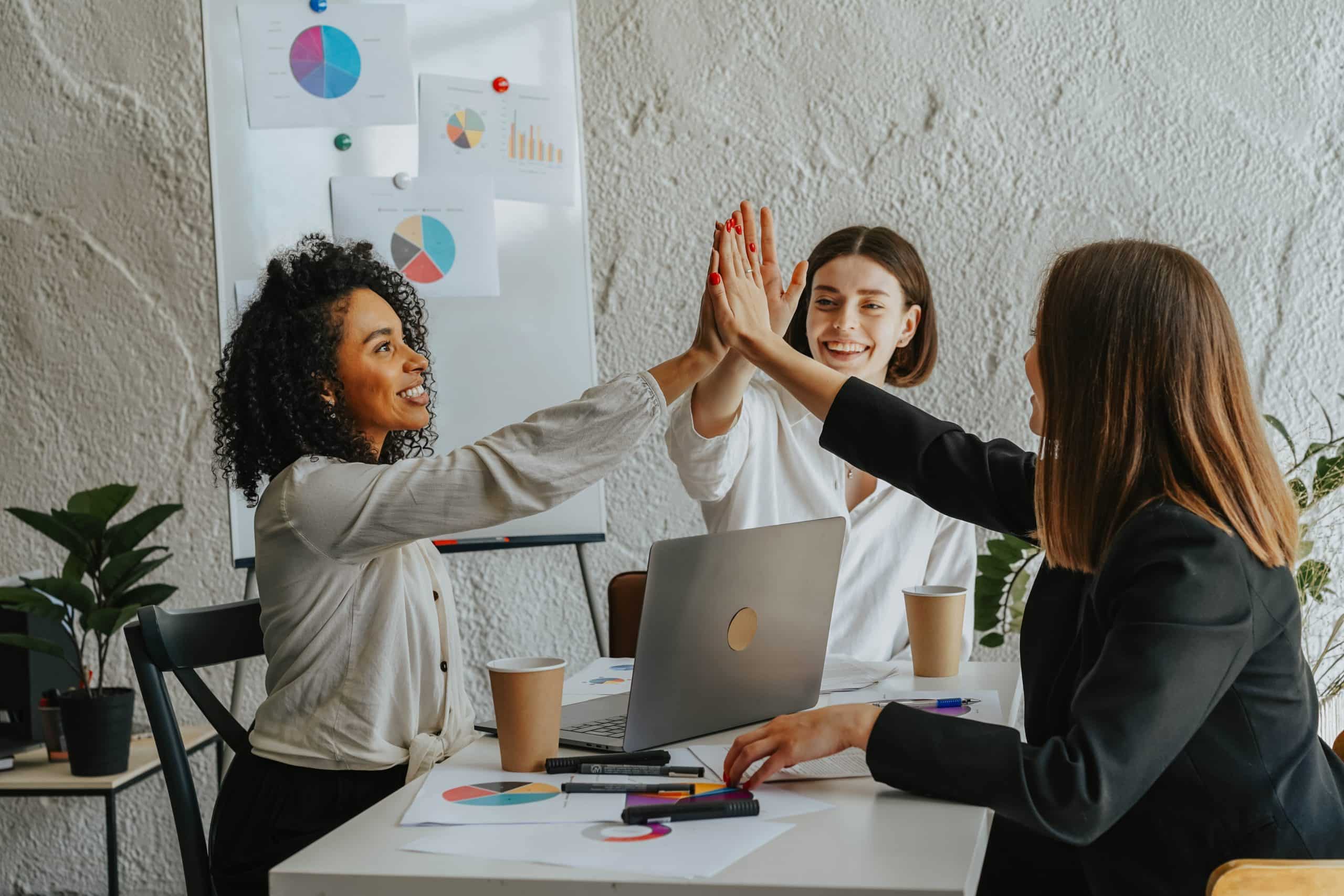 Three women in a business meeting high five