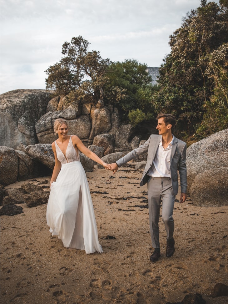 Bride and groom holding hands on beach at destination wedding
