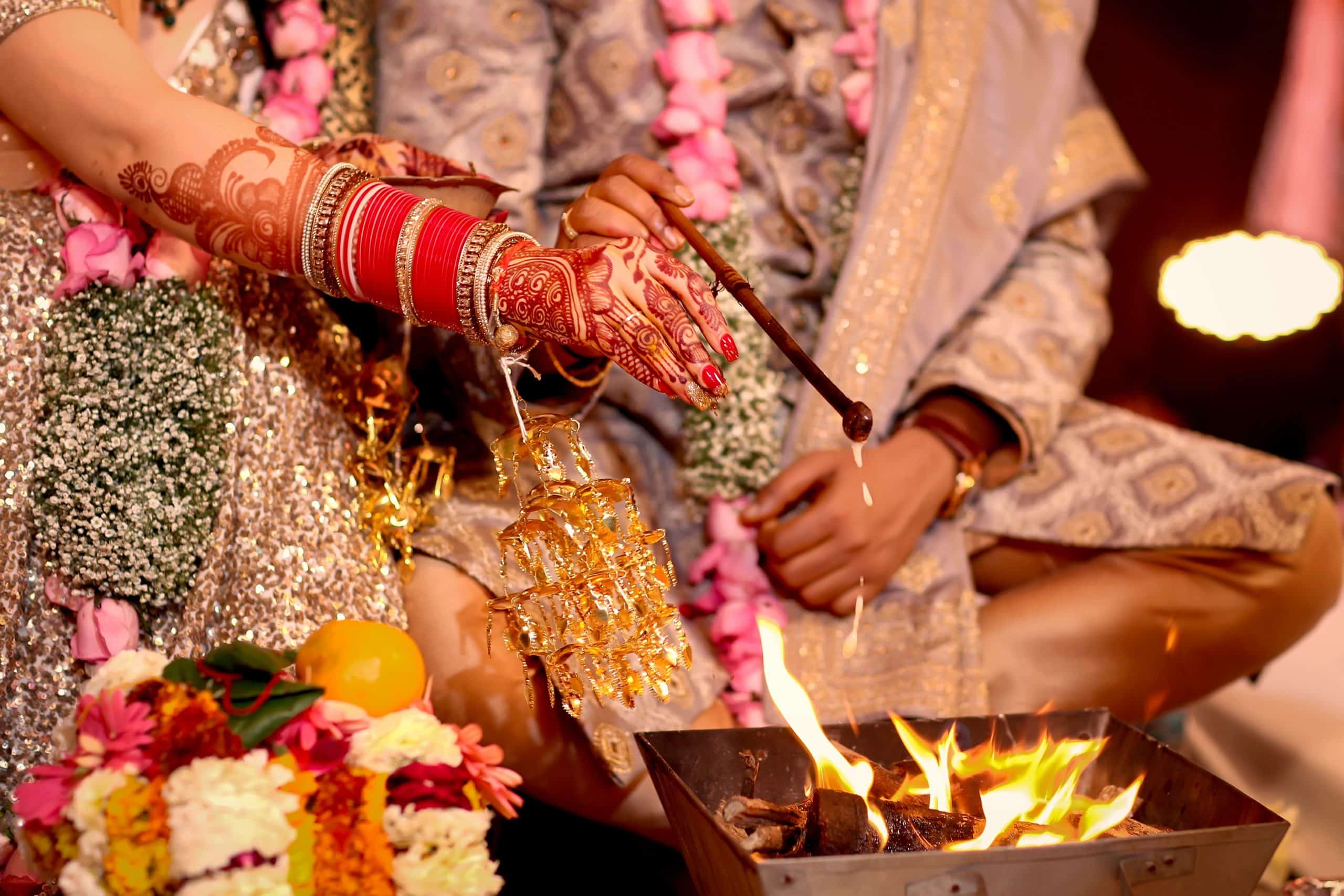 Indian bride and groom pour ghee into a fire during their destination wedding ceremony.