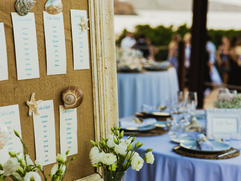 Wedding seating chart on burlap decorated with shells.