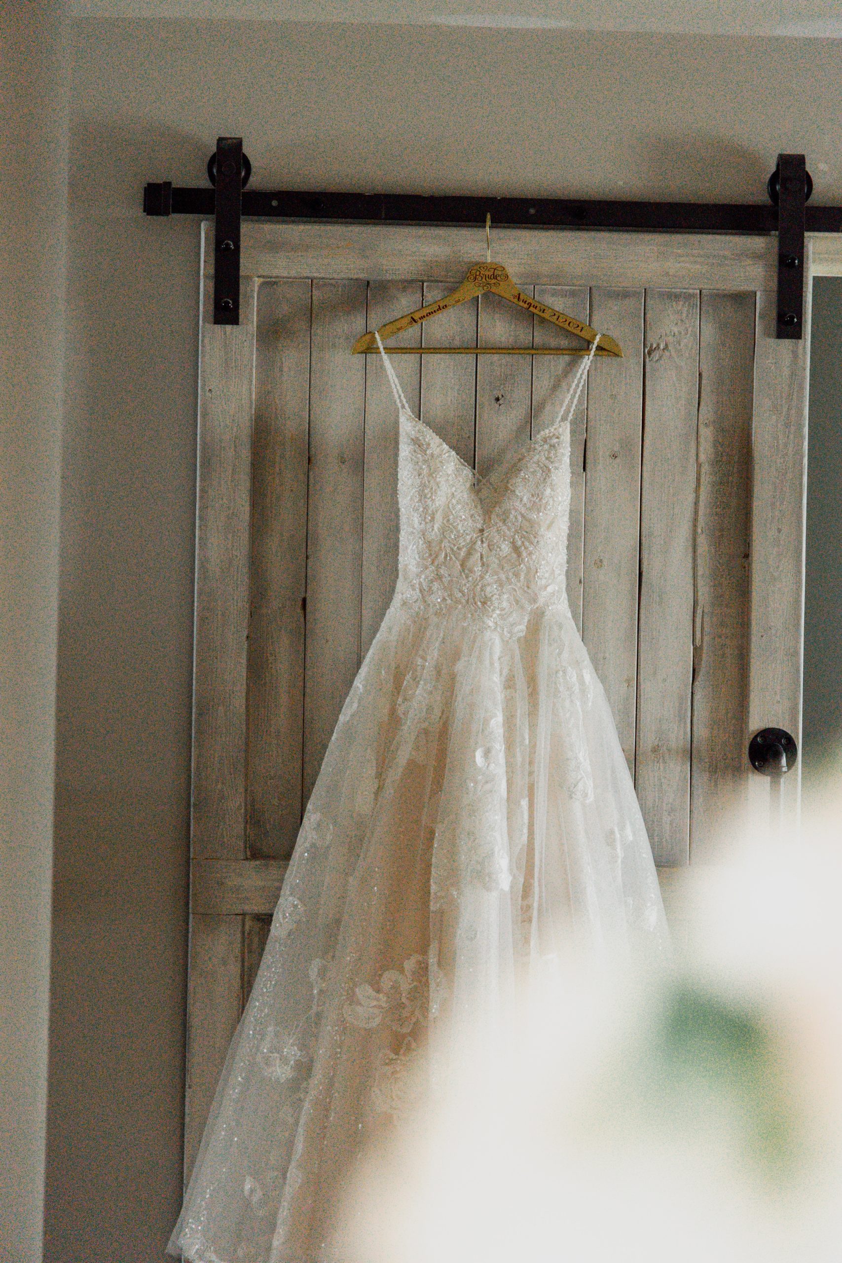 An A-line, lace wedding dress hangs off of a door.