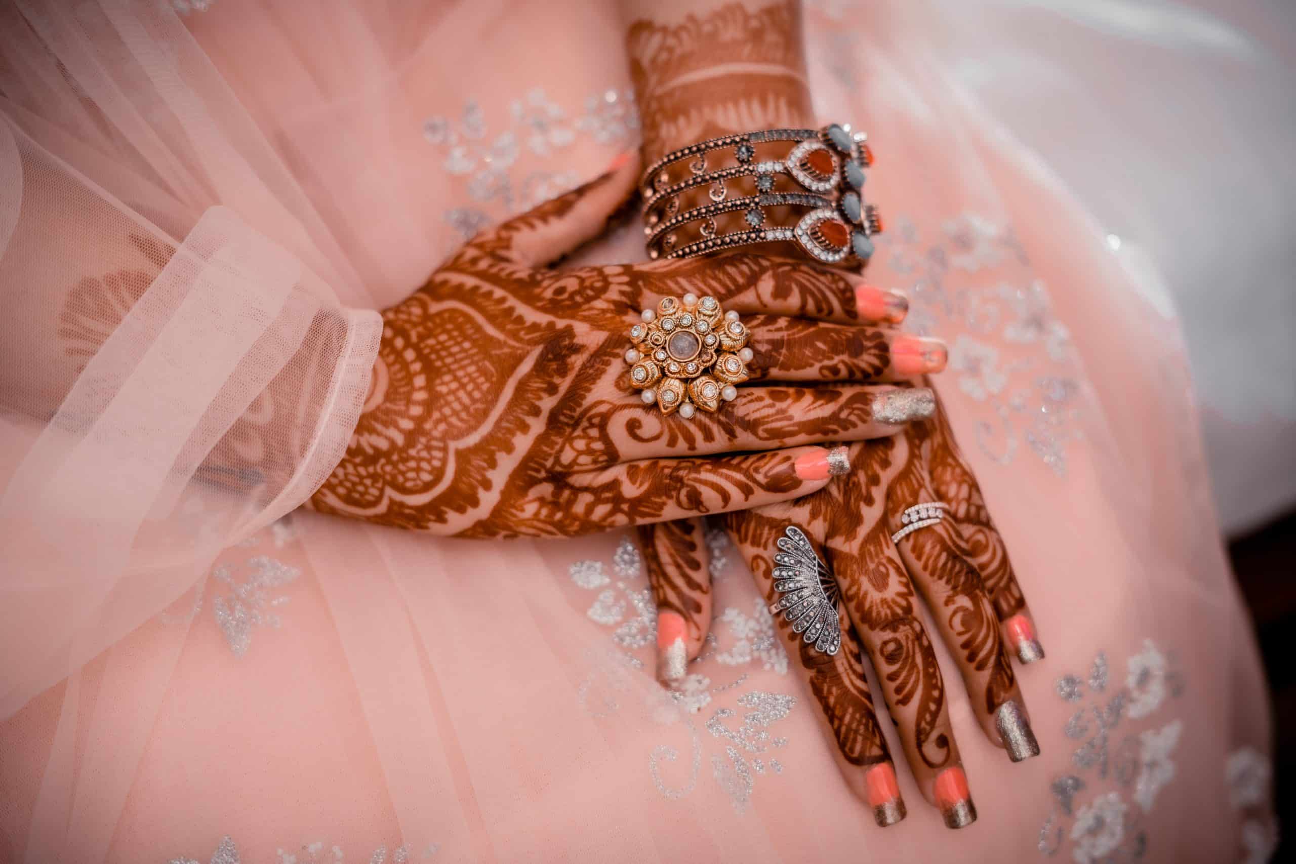 Close-up of a woman's hands with mehndi and jewelry.