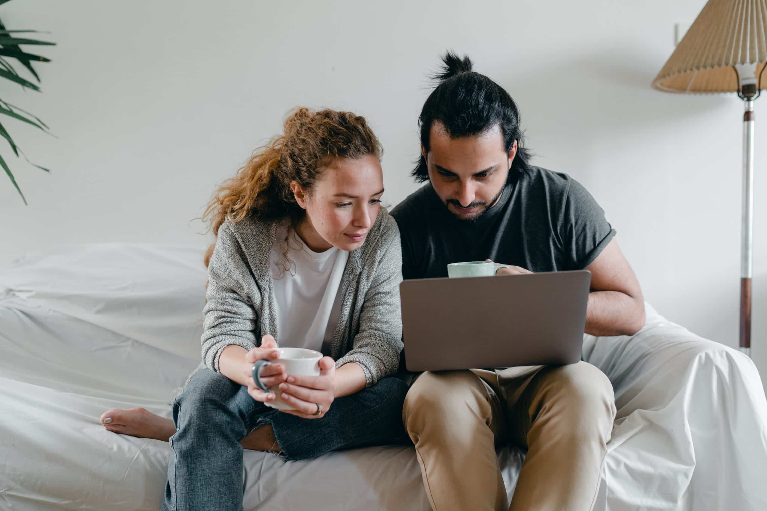 Concentrated couple browsing laptop on sofa