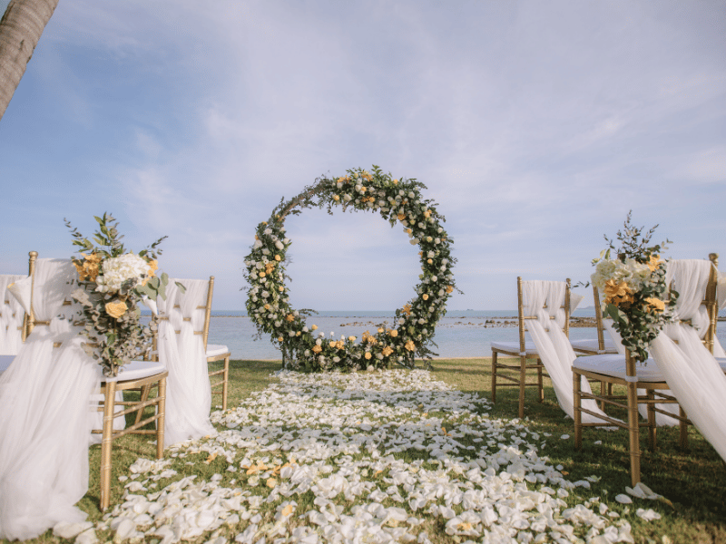 A circular wedding arch and ceremony setup beside a beach.