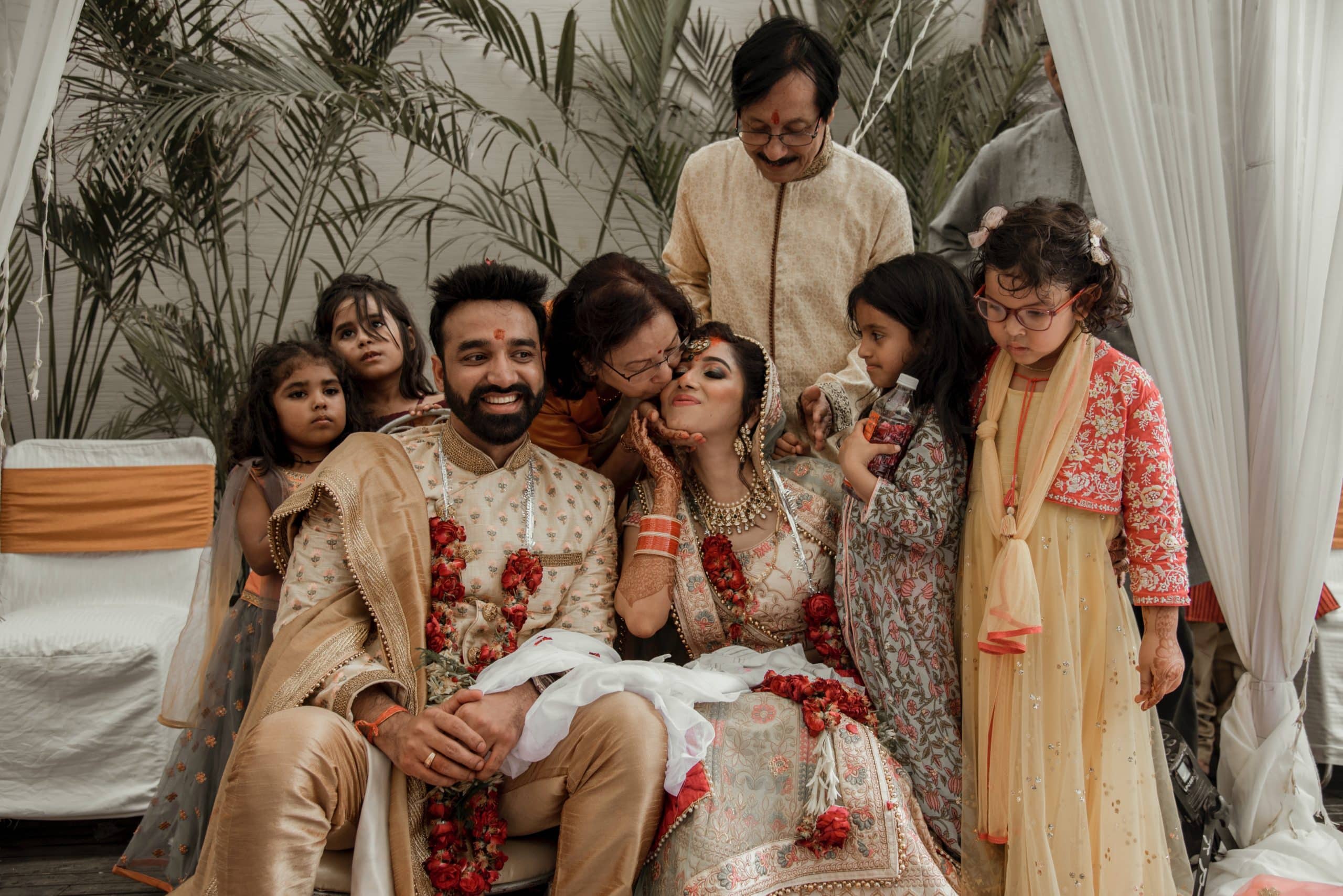 Indian family sits on a wedding stage with the bride and groom.
