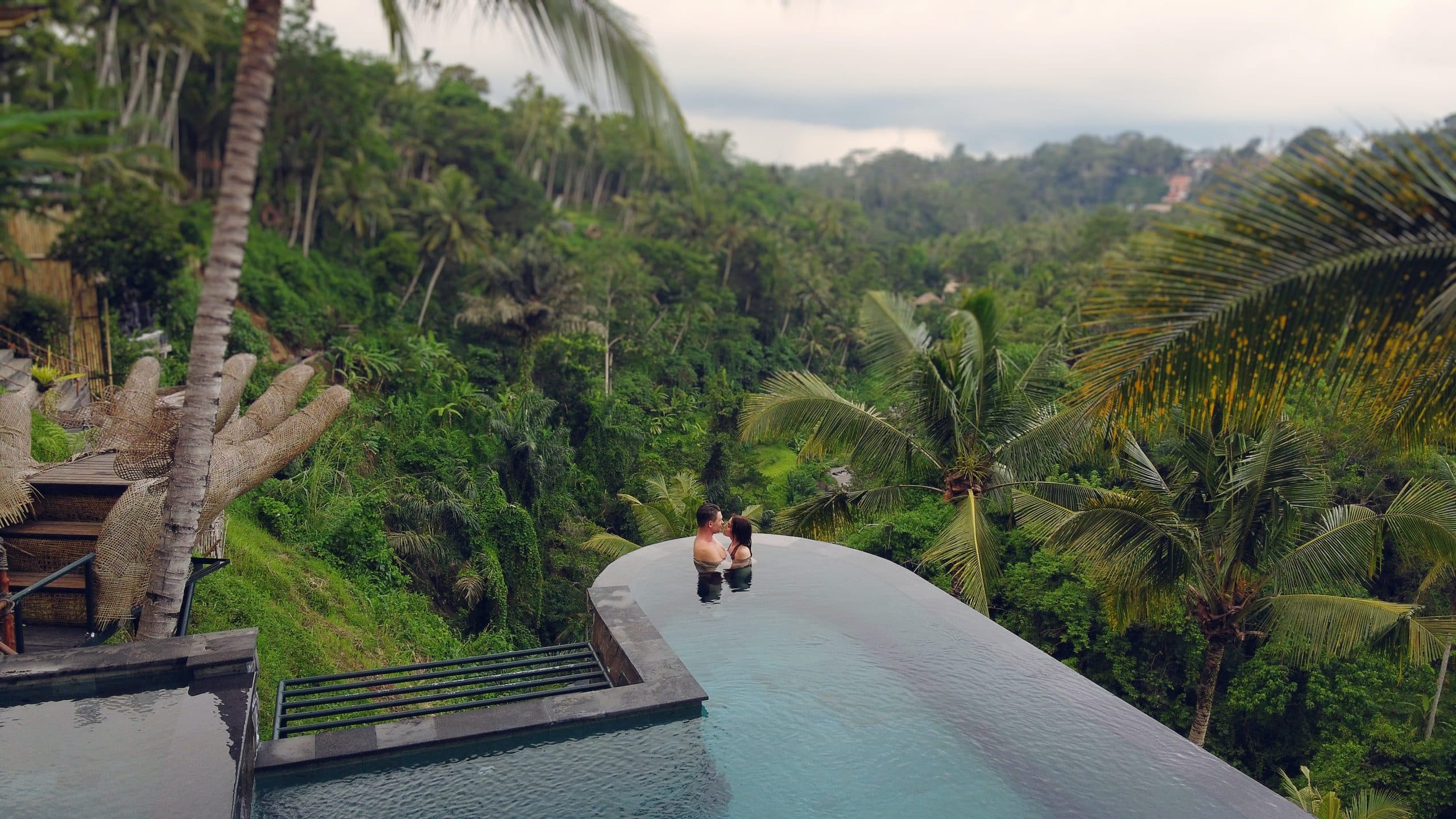 Honeymoon couple kisses in an infinity pool overlooking the jungle