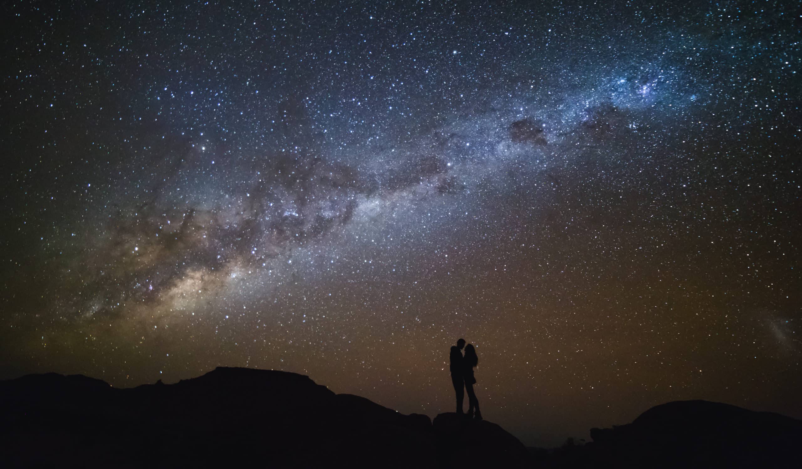 Landscape in Hawaii with Milky Way. Night sky with stars and silhouette of a couple kissing on the mountain.