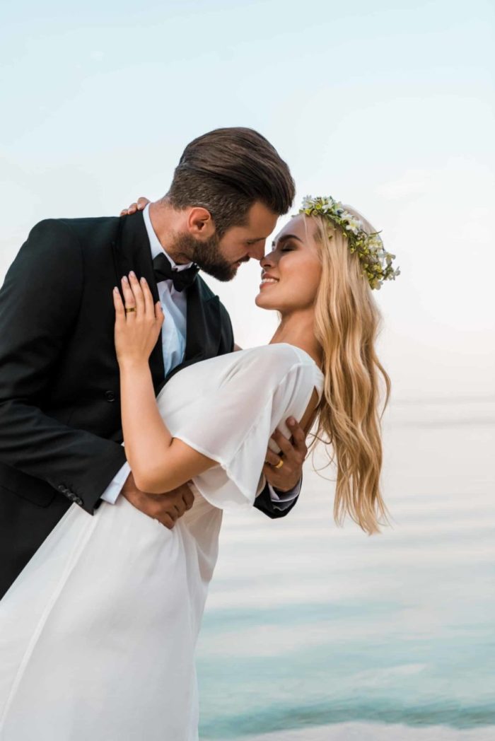 affectionate destination wedding couple going to kiss on beach