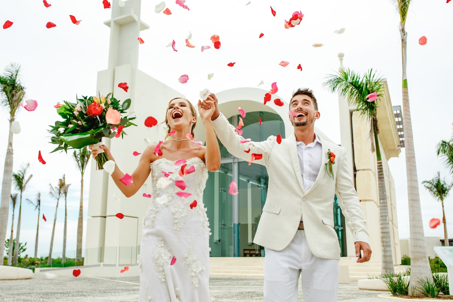 Destination wedding couple leaving church in Mexico while showered with rose petals