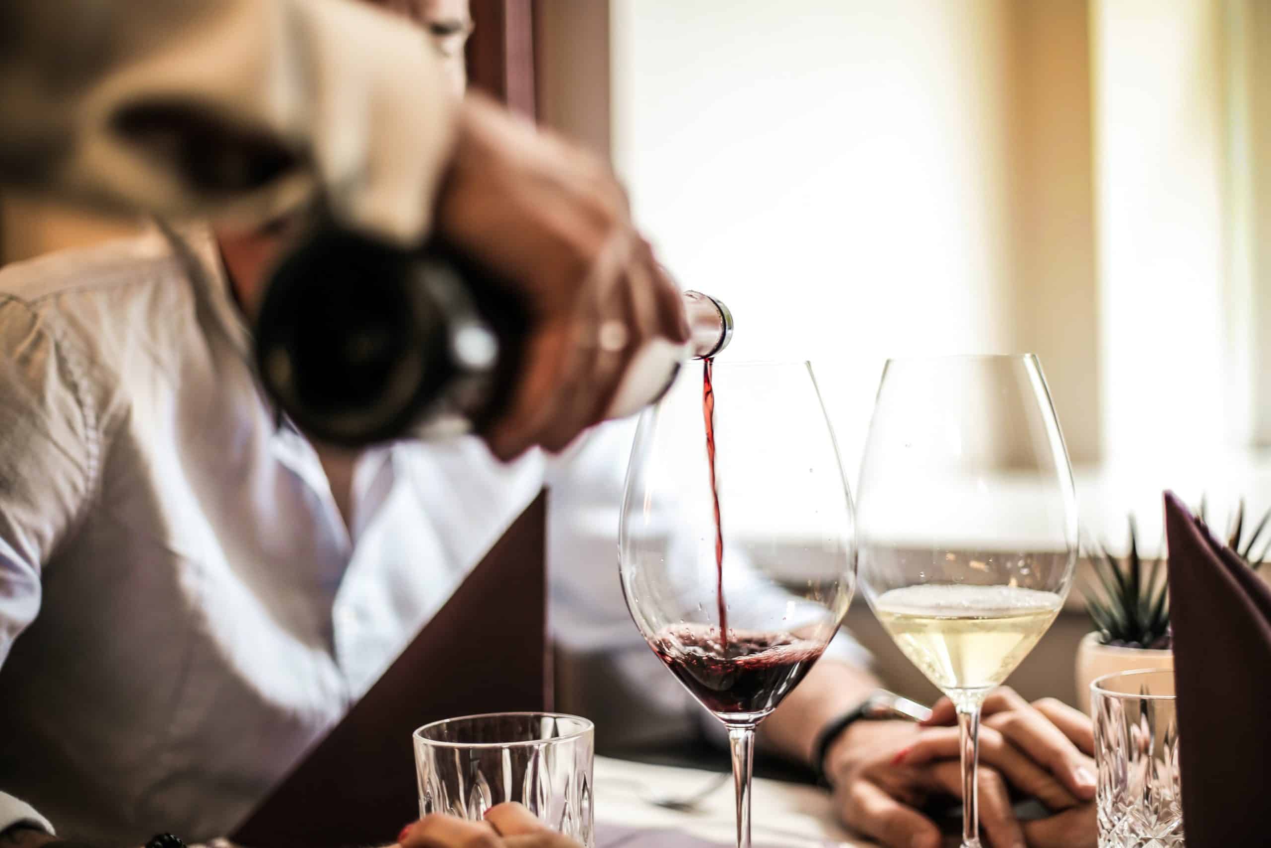 Close-up of a waiter pouring wine into a glass