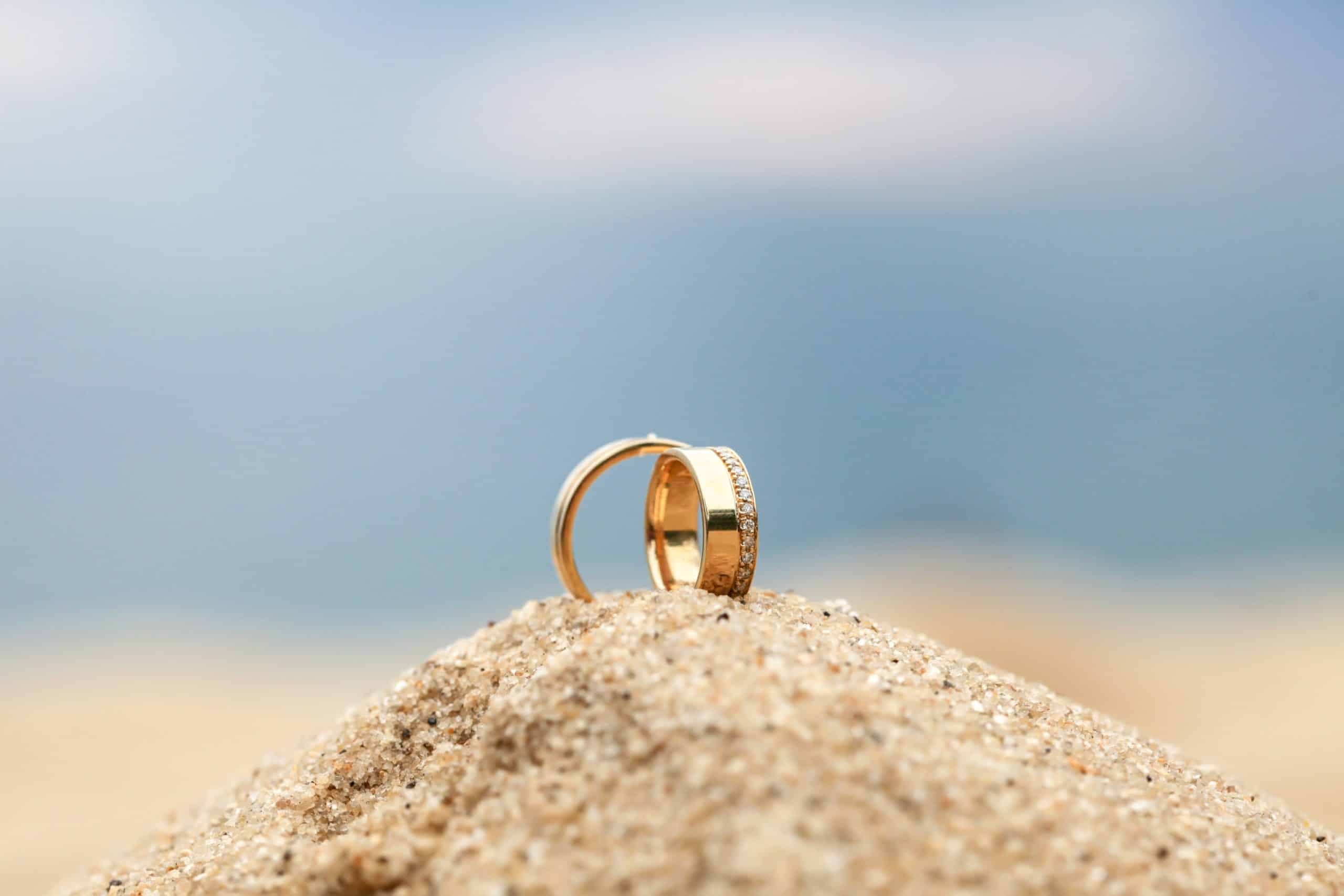 Wedding rings sit atop a pile of sand on the beach