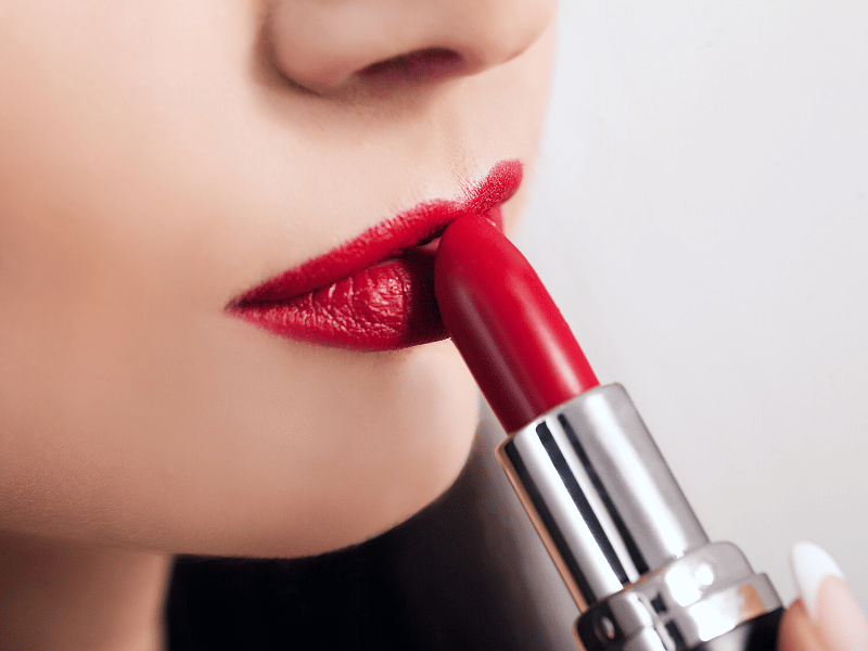 Close-up of woman applying red lipstick
