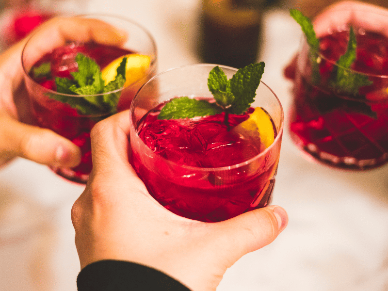 Three wedding guests hold glasses of red sangria